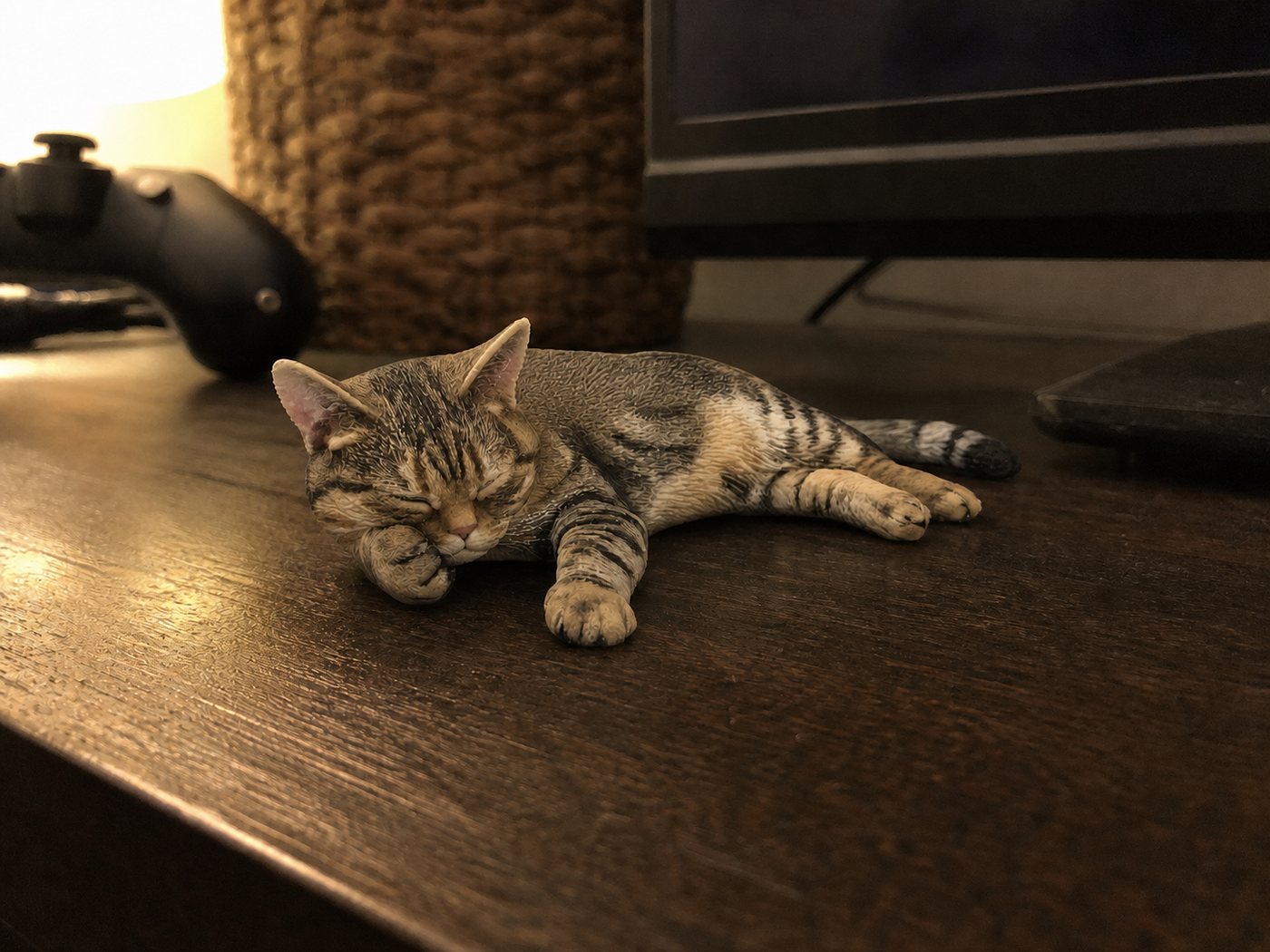 テレビ台の上で寝そべる、キジトラ猫のフィギュア